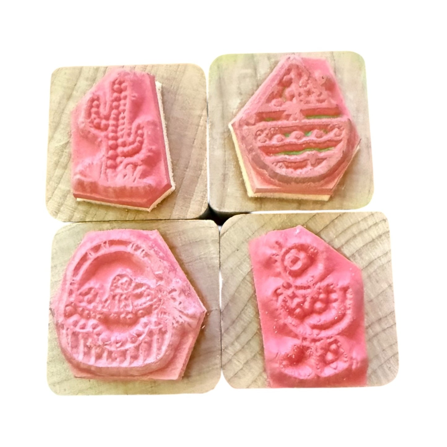Four pink stamps with embossed designs on wooden blocks.