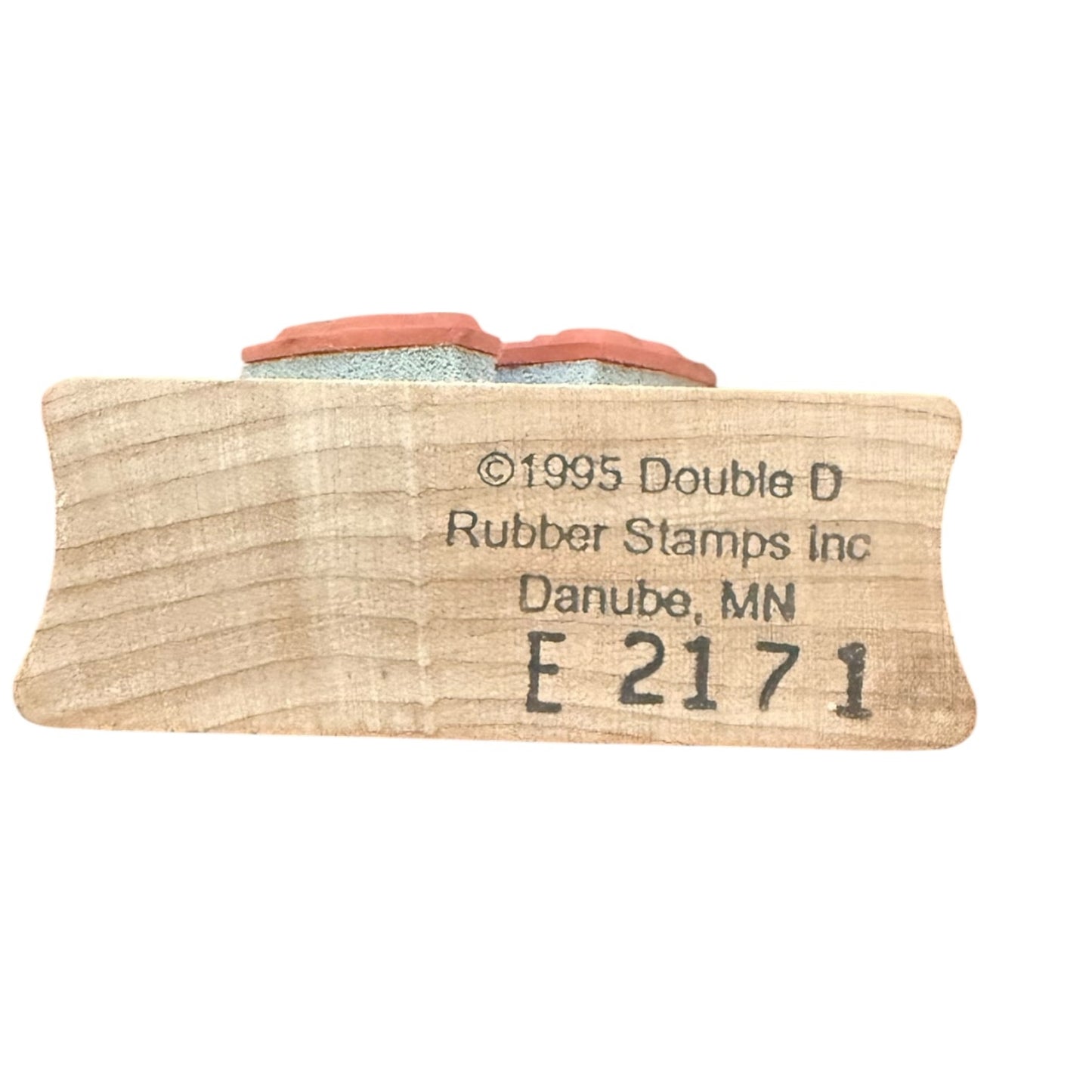 A wooden stamp block featuring a terracotta-colored rubber stamp , engraved with 'Double D Rubber Stamps Inc' and 'E 2171'.