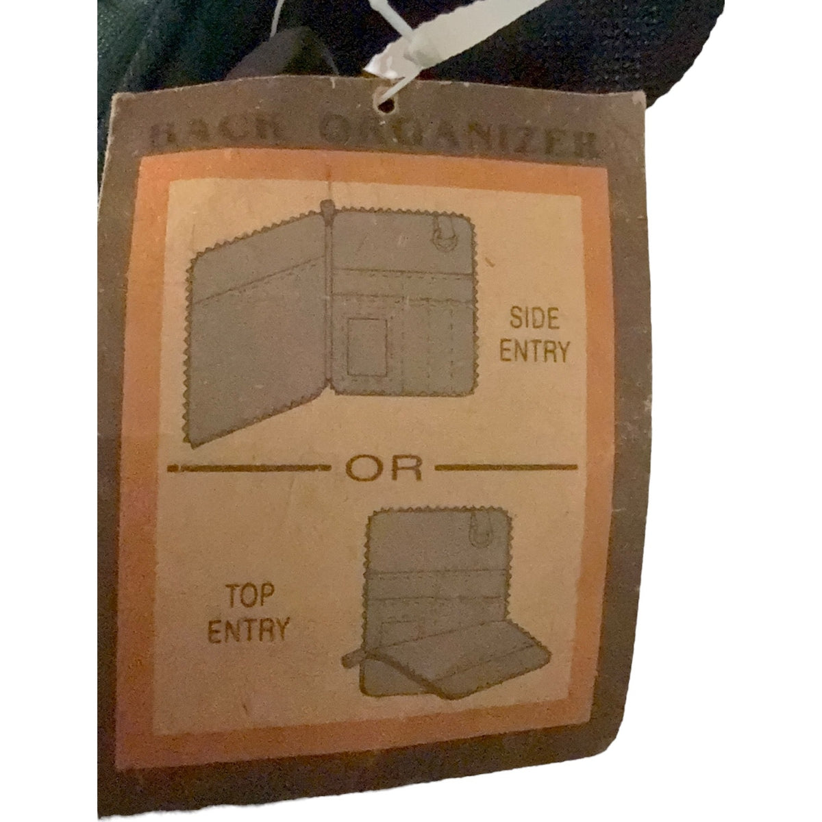 A close-up of a product tag for a back organizer, showing printed diagrams of side entry or top entry, with a dark fabric item attached at the top.