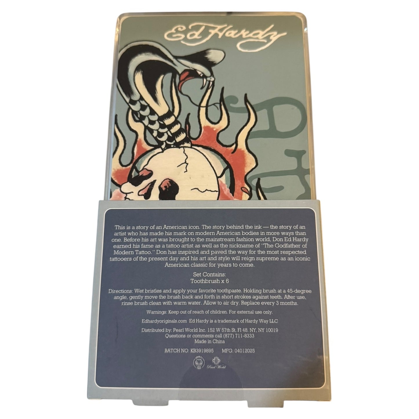 Ed Hardy Toothbrush x 6 collaboration plaque featuring a traditional American tattoo style illustration of a toothbrush with flames and the text 'Ed Hardy' at the top, with a detailed product description plaque at the bottom.