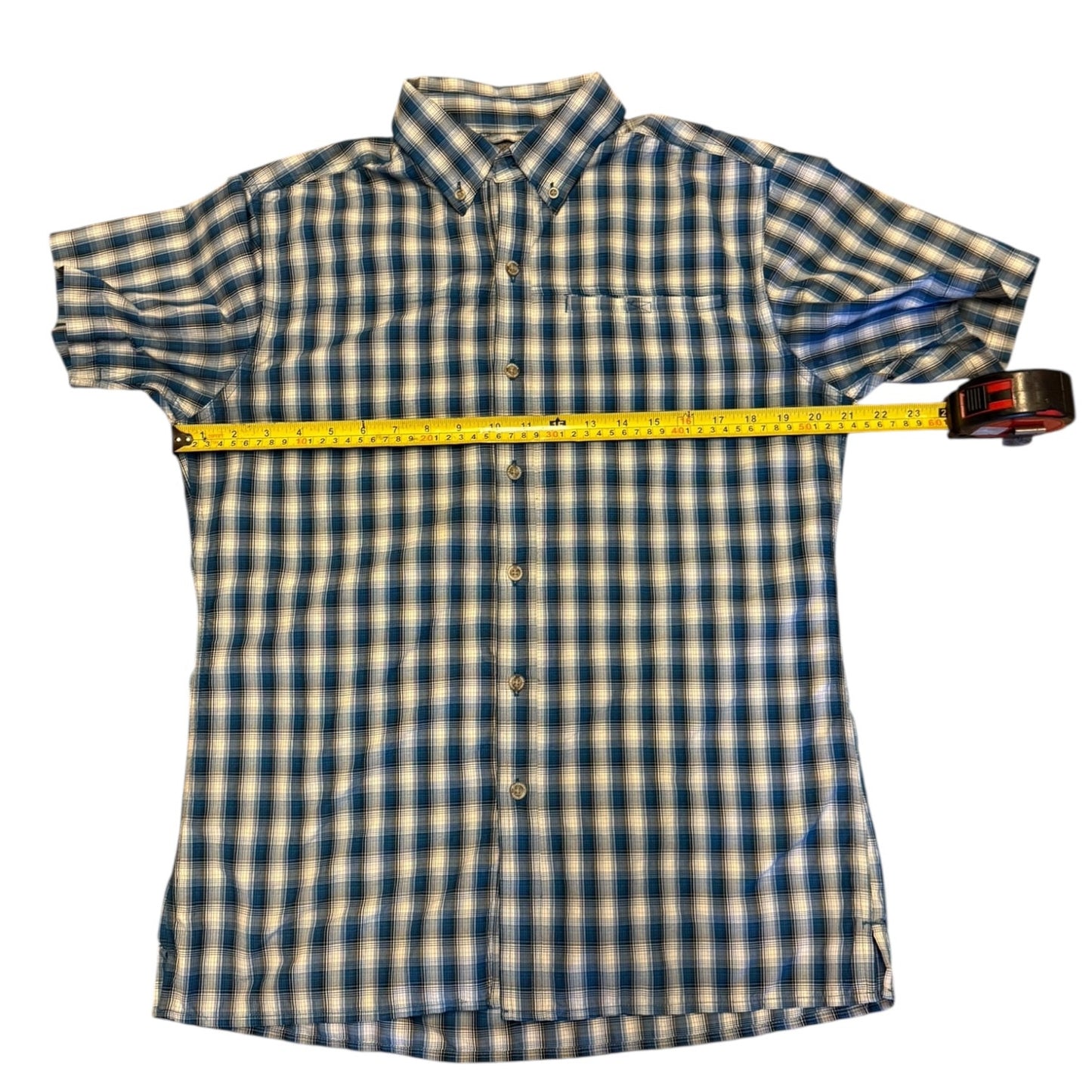 Blue and white shirt with a yellow measuring tape laying pit to pit on a white background