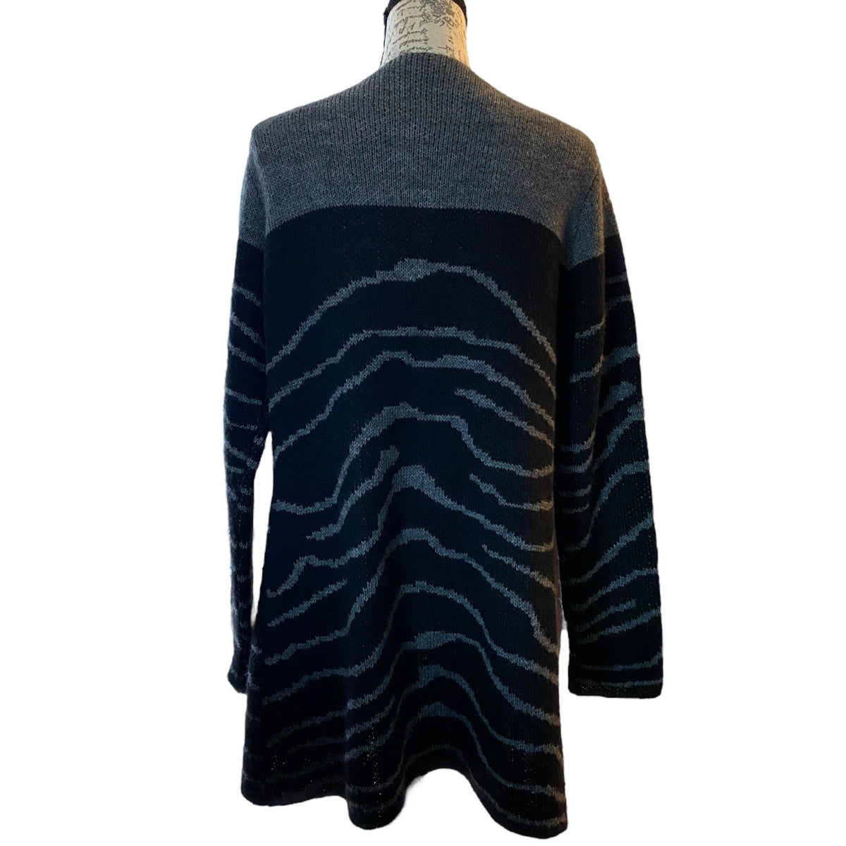A long-sleeve knit sweater shown from the back on a mannequin, featuring a color-blocked design with a dark gray upper and black & gray lower body with a wavy zebra-like stripe pattern.
