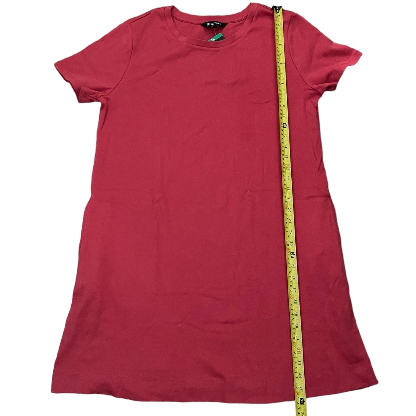 A red short-sleeve t-shirt dress laid flat on a white background, with a yellow measuring tape running vertically from the collar to the hem to show the length.