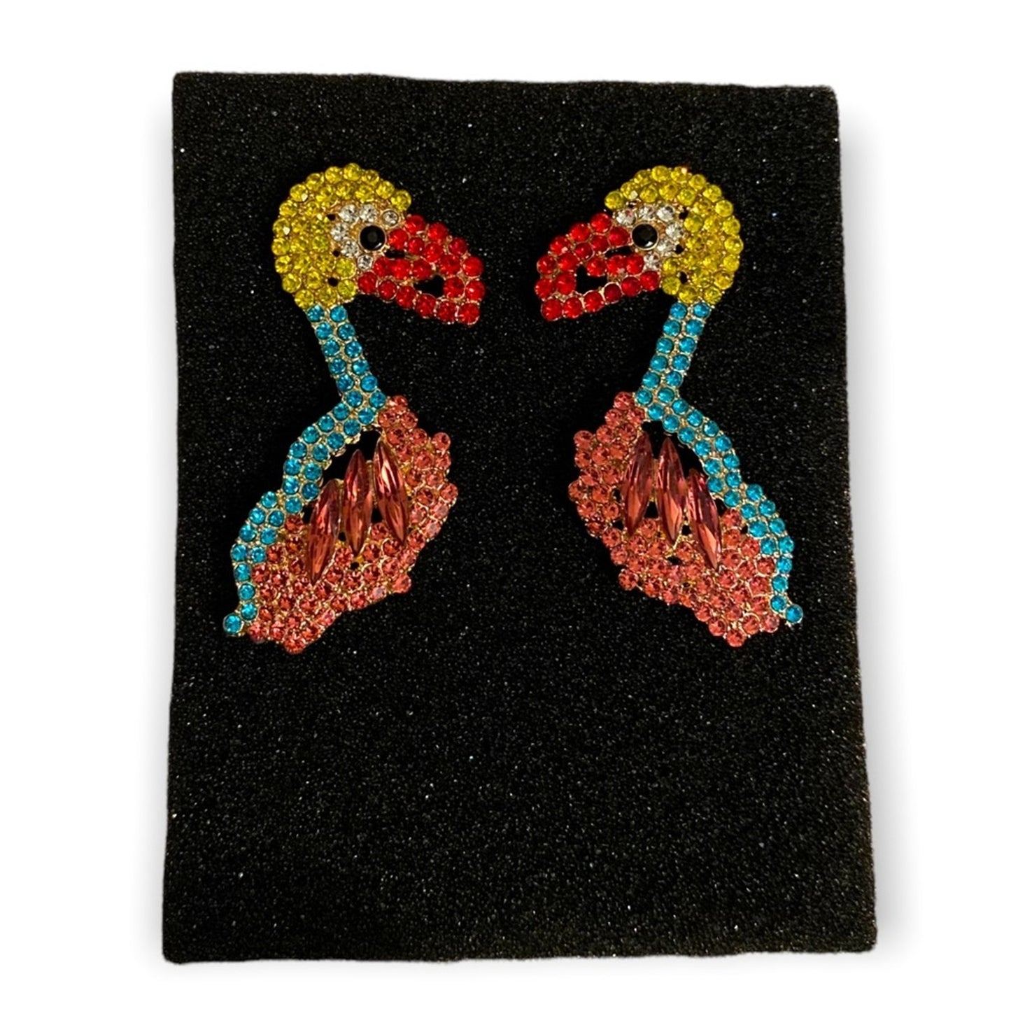 Colorful earrings of a bird on a black foam on a white background