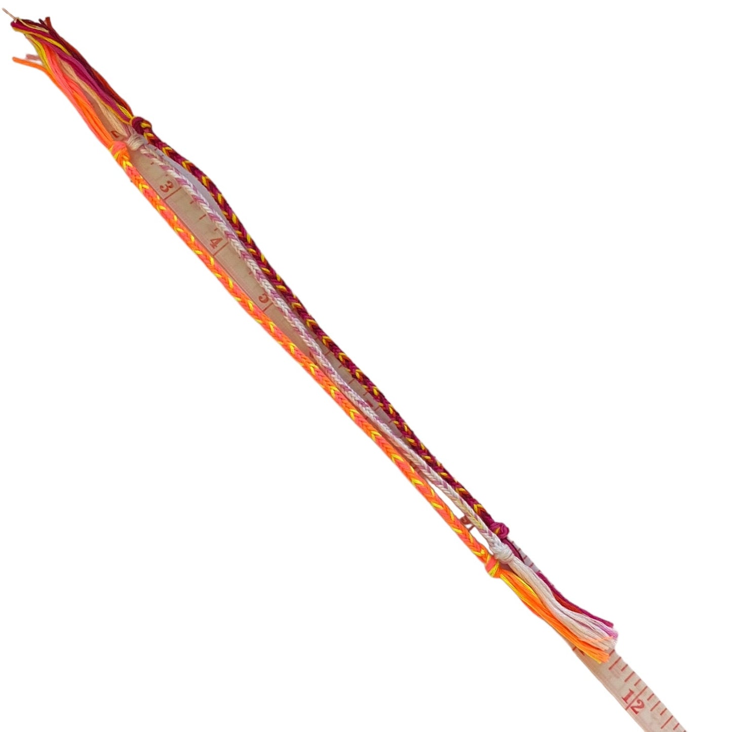 A handmade braided friendship bracelet made in multi colors, shown diagonally on a plain white background with a measuring tape attached to the end.