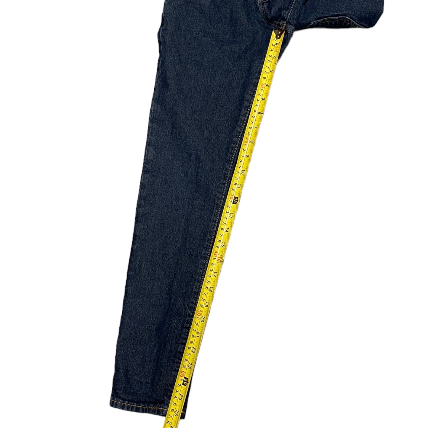 A close-up of a dark blue denim jeans leg with a yellow measuring tape running vertically down the side to show the inseam or length measurement, on a plain white background.
