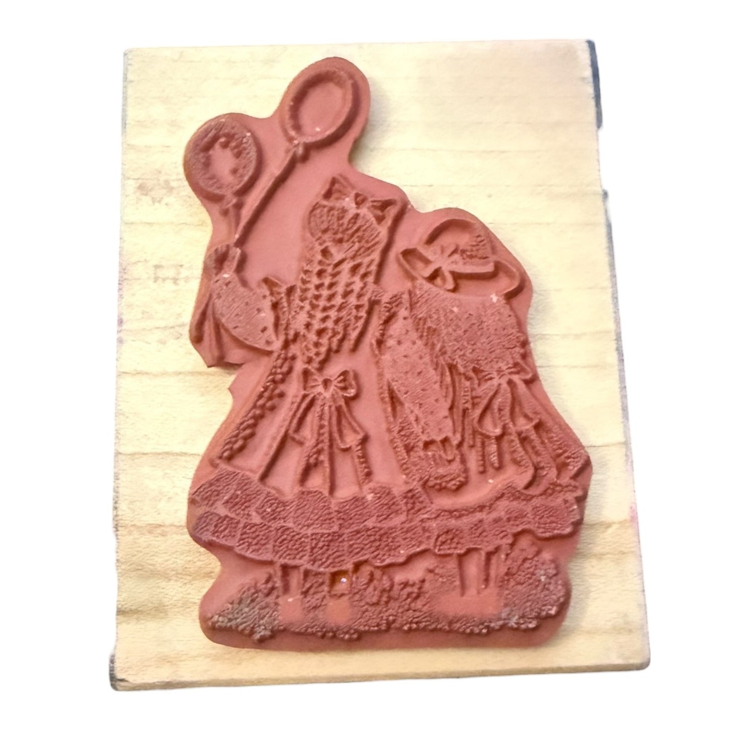 Decorative rubber stamp with a design of a woman holding balloons on a wooden block.