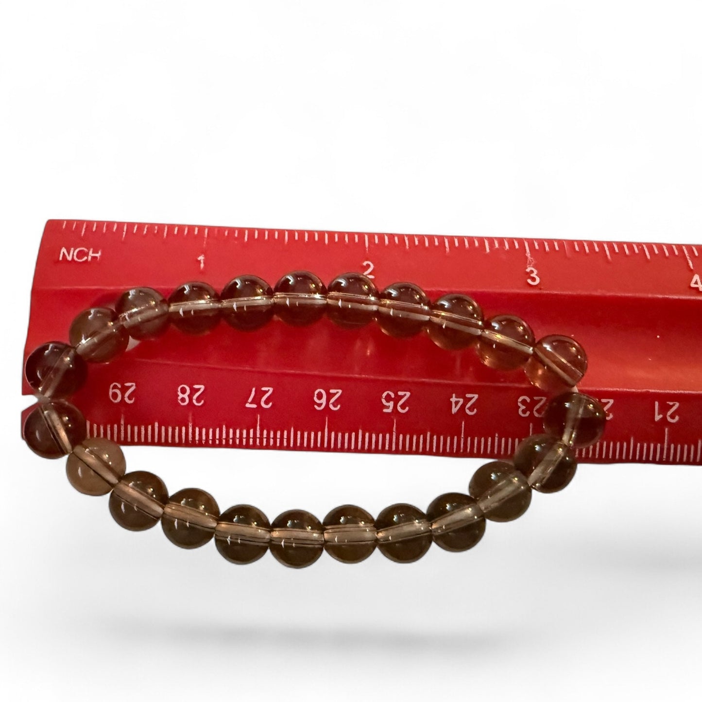 Smoke beaded bracelet on a red ruler against a white background
