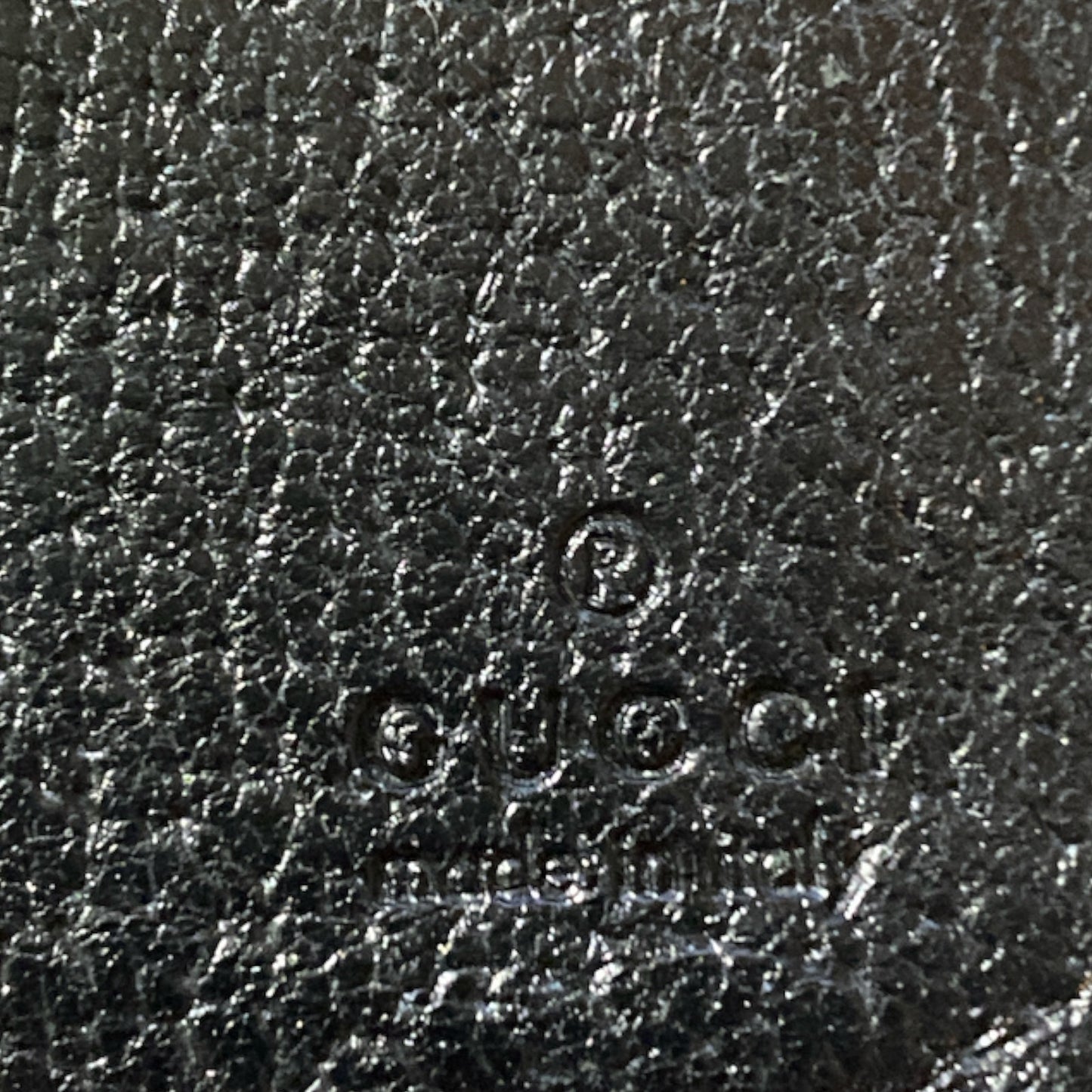 Close-up of Gucci logo on black leather texture