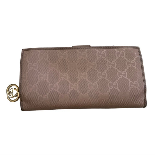 A pink Gucci monogram canvas clutch wallet with a gold-tone interlocking G charm on the side, shown against a plain white background.
