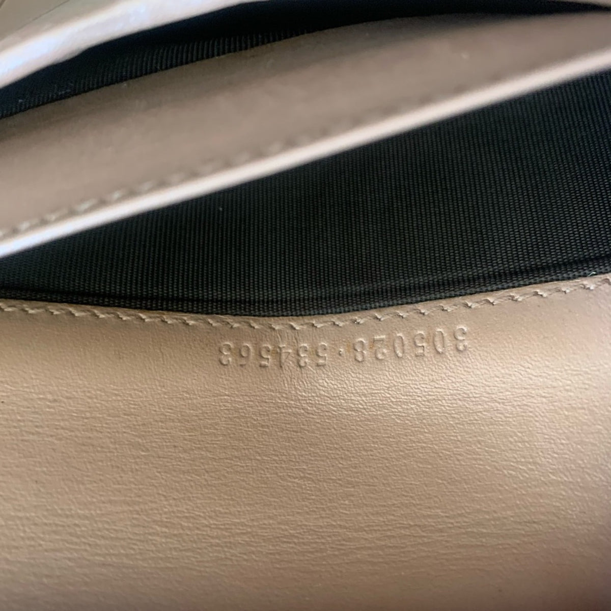 Close-up of a leather product interior showing a black fabric lining and stamped serial numbers '305028-534563'.