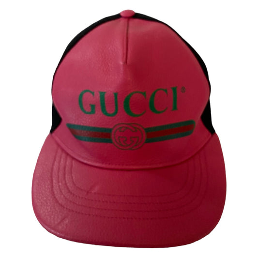 A pink leather-texture trucker cap with black mesh back panels, featuring green 'GUCCI' lettering and the iconic green and red web stripe with the GG logo on the front.