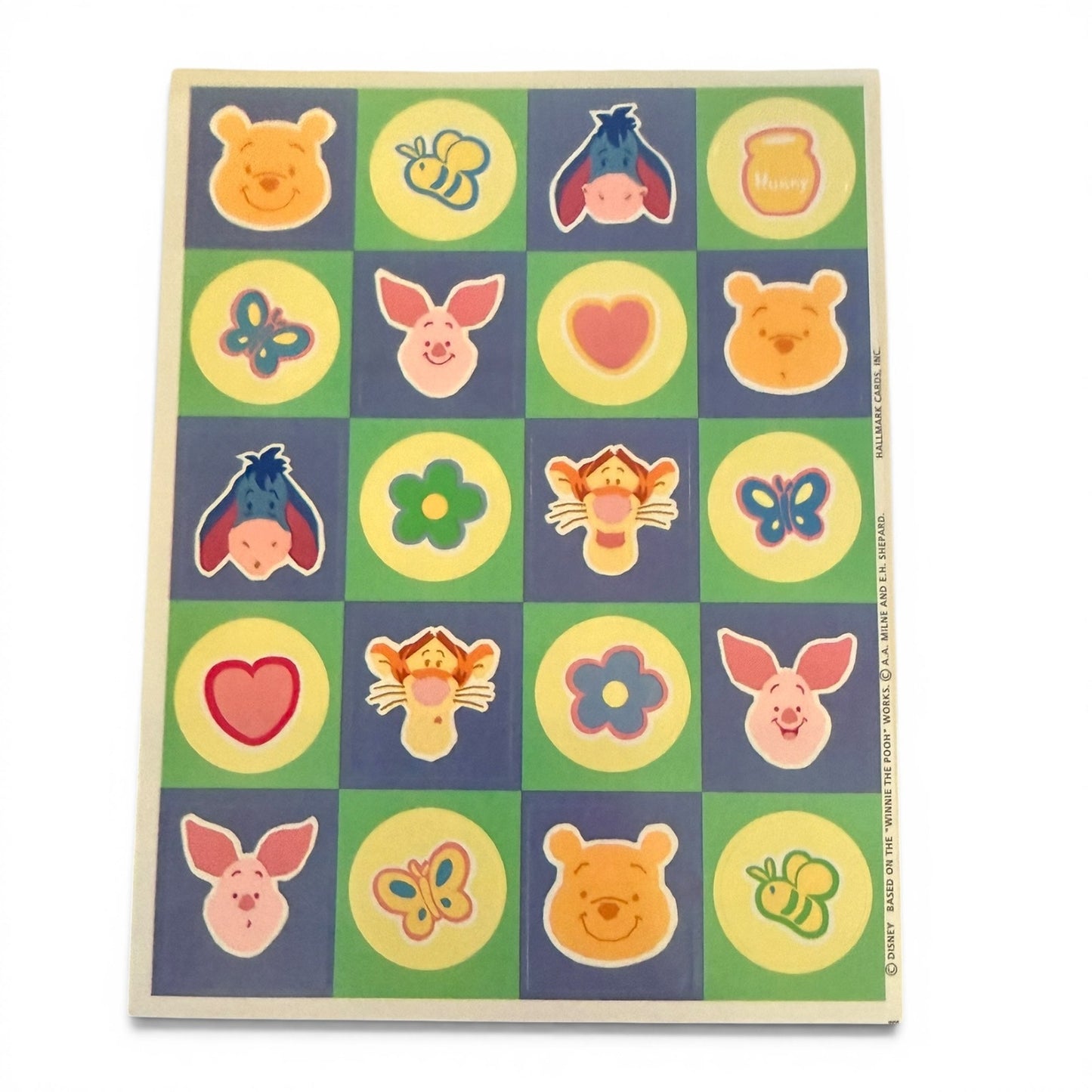 Colorful checkered sheet with cartoon character faces stickers on a white background