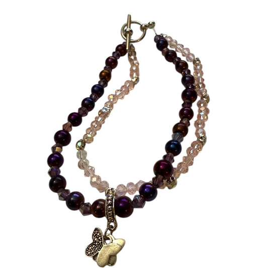 A double-strand beaded bracelet with dark purple and pink faceted beads, metal hardware, and a dangling butterfly charm, shown on a plain white background.