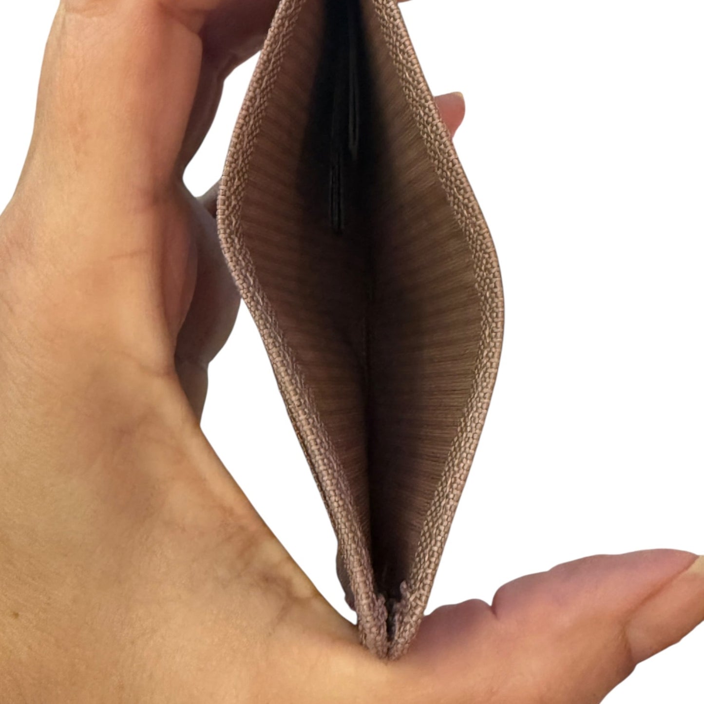 A close-up of a hand holding an open slim cardholder wallet, showing the tan woven fabric exterior and striped interior lining against a plain white background.