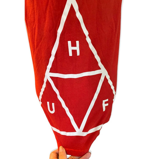 Side view of red shirt with white geometric design and 'HUF' branding on a white background