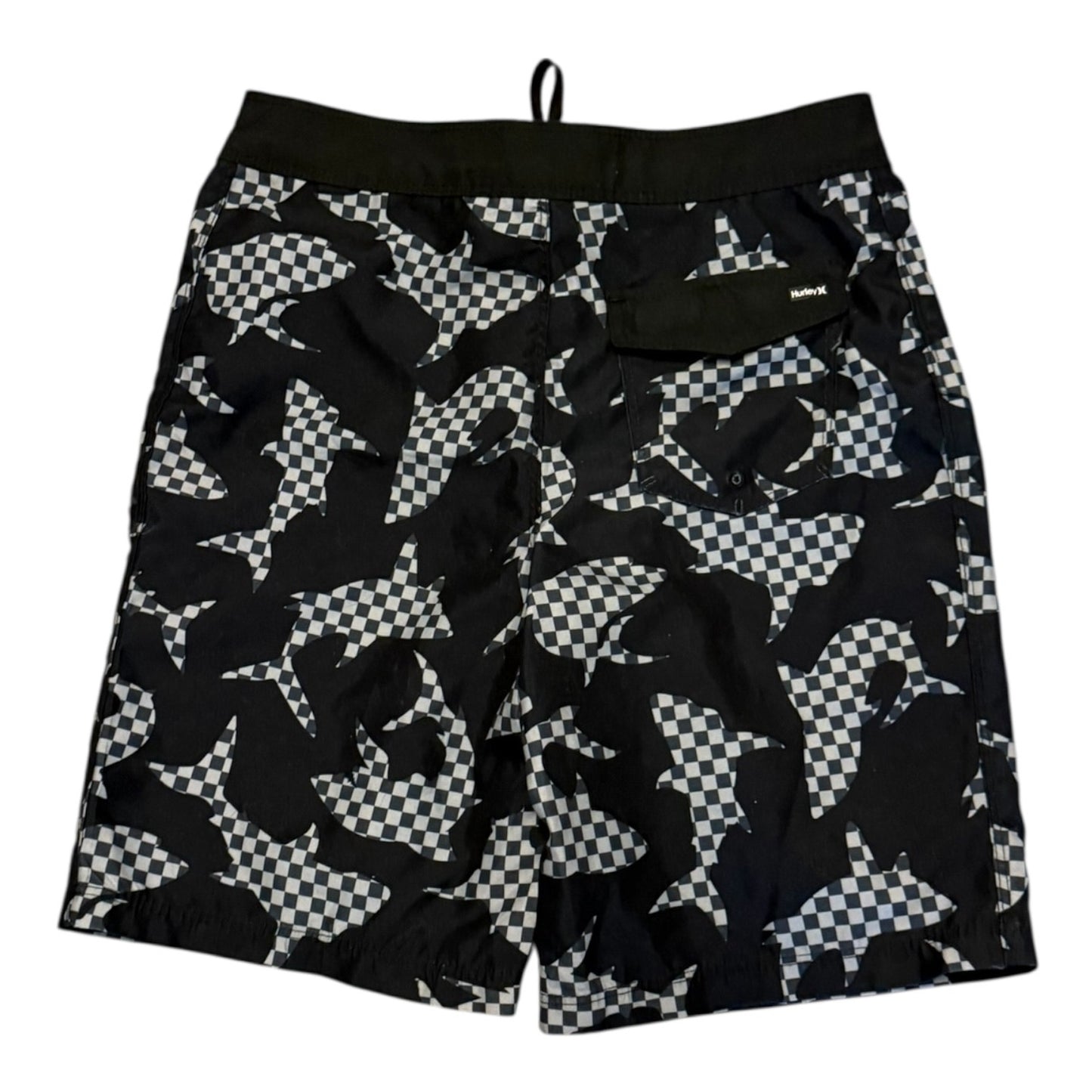 Black and gray patterned swim trunks with a shark print and checkerboard details, featuring a black elastic waistband and a side pocket.