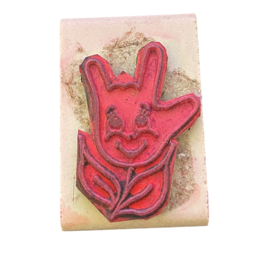 Red hand-shaped stamp on a beige block with a white background