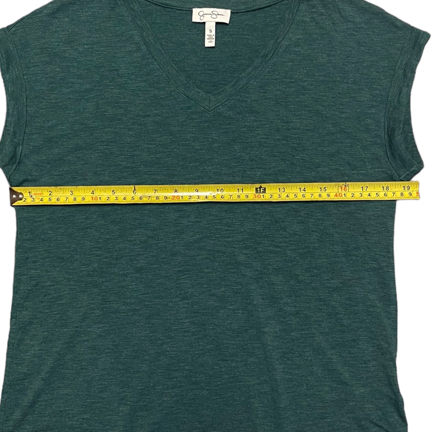 Green short sleeve shirt with a yellow measuring tape laying across it on a white background