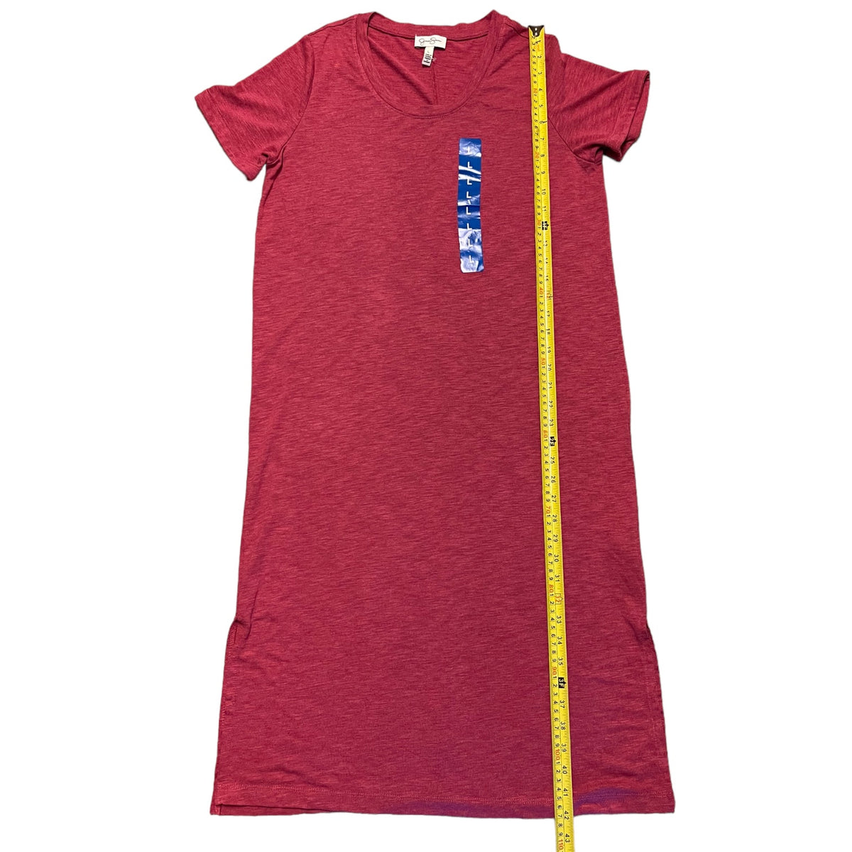 A heathered red short-sleeve t-shirt dress laid flat on a white background, with a yellow tape measure running vertically down the center to show the garment's length.