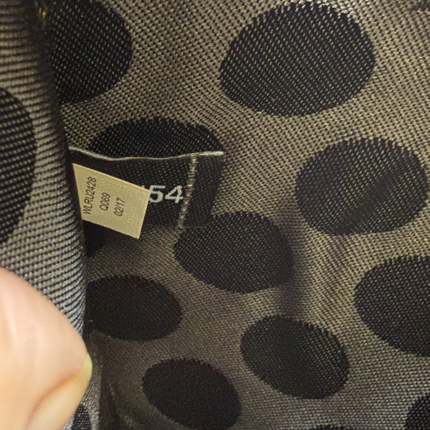 Close-up of a black fabric on wallet with a pattern and a visible tag.