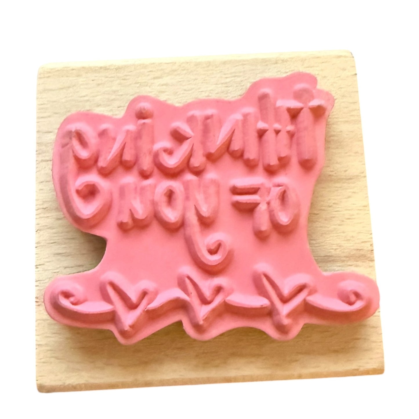 A pink rubber stamp , mounted on a square light wood block.