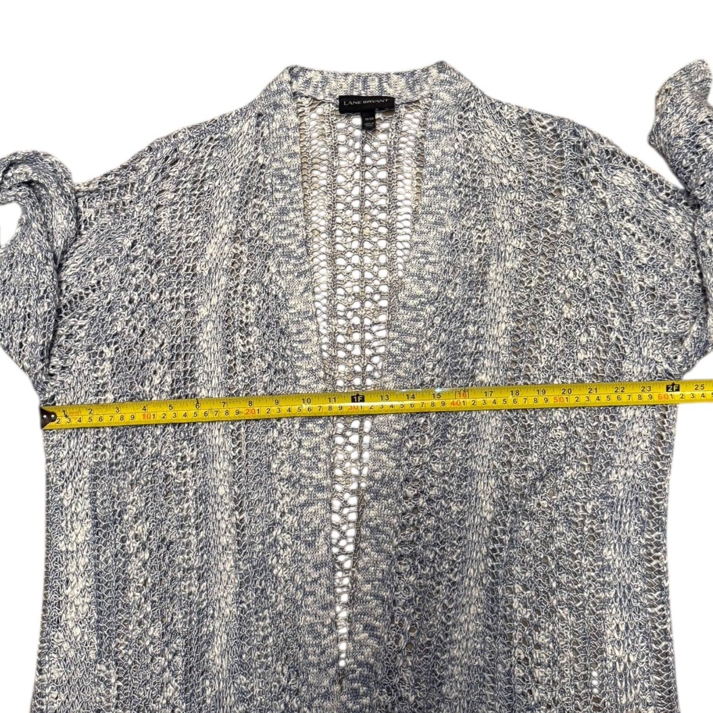 Blue knit front cardigan with a measuring tape across it on a white background