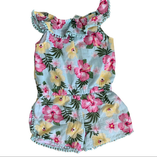 A toddler romper with a tropical floral print on a light blue background, featuring pink and yellow hibiscus flowers and green leaves.