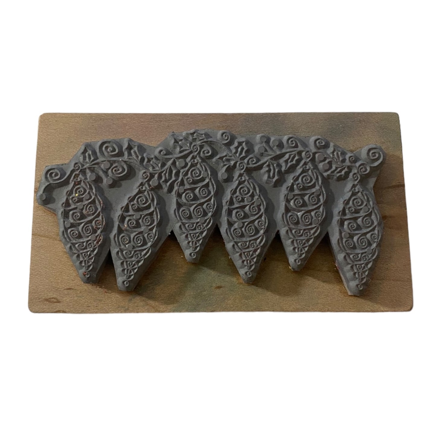 A gray holiday rubber stamp, displayed on a rectangular wooden board against a white background.
