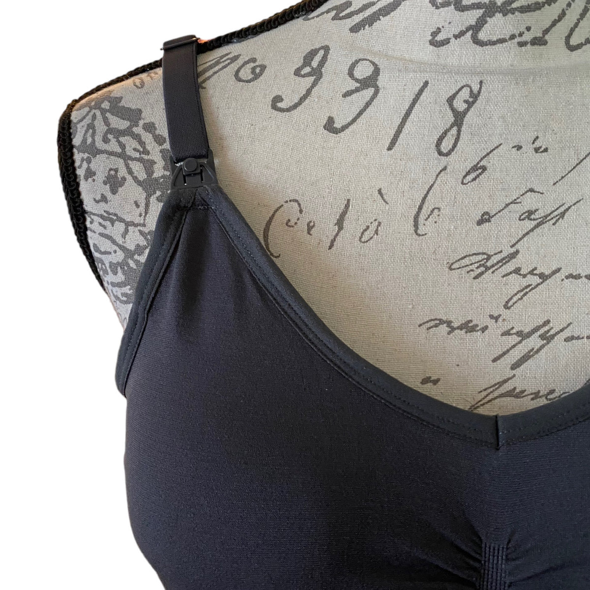 A close-up of a gray tank top displayed on a vintage-style printed fabric dress form against a white background.
