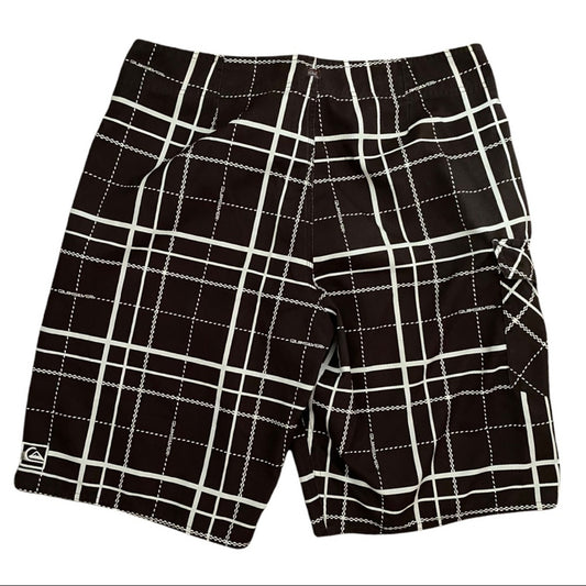 Brown and white plaid board shorts with a small Quiksilver logo on the lower left hem, displayed flat against a white background.