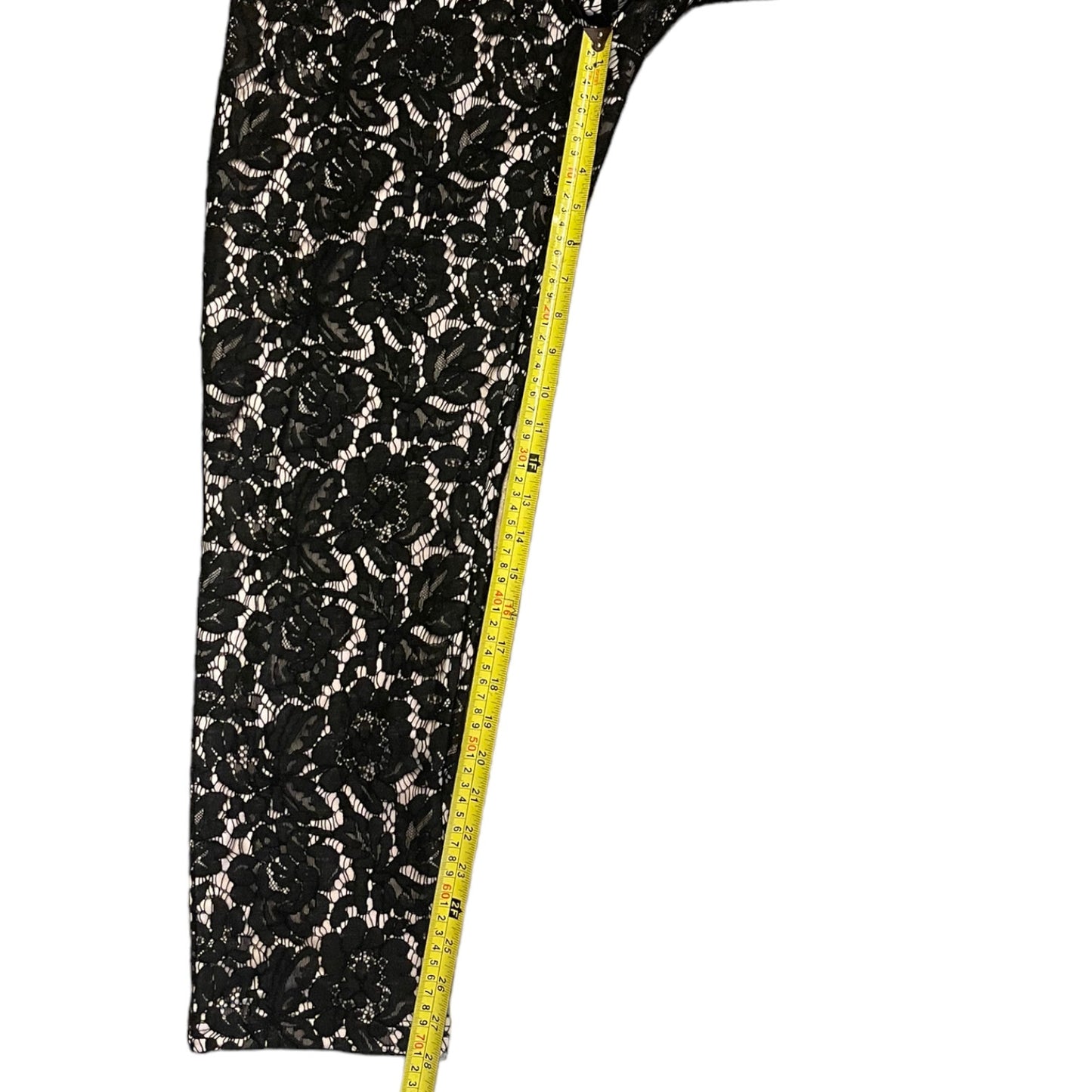 Black floral lace fabric with a measuring tape on a white background