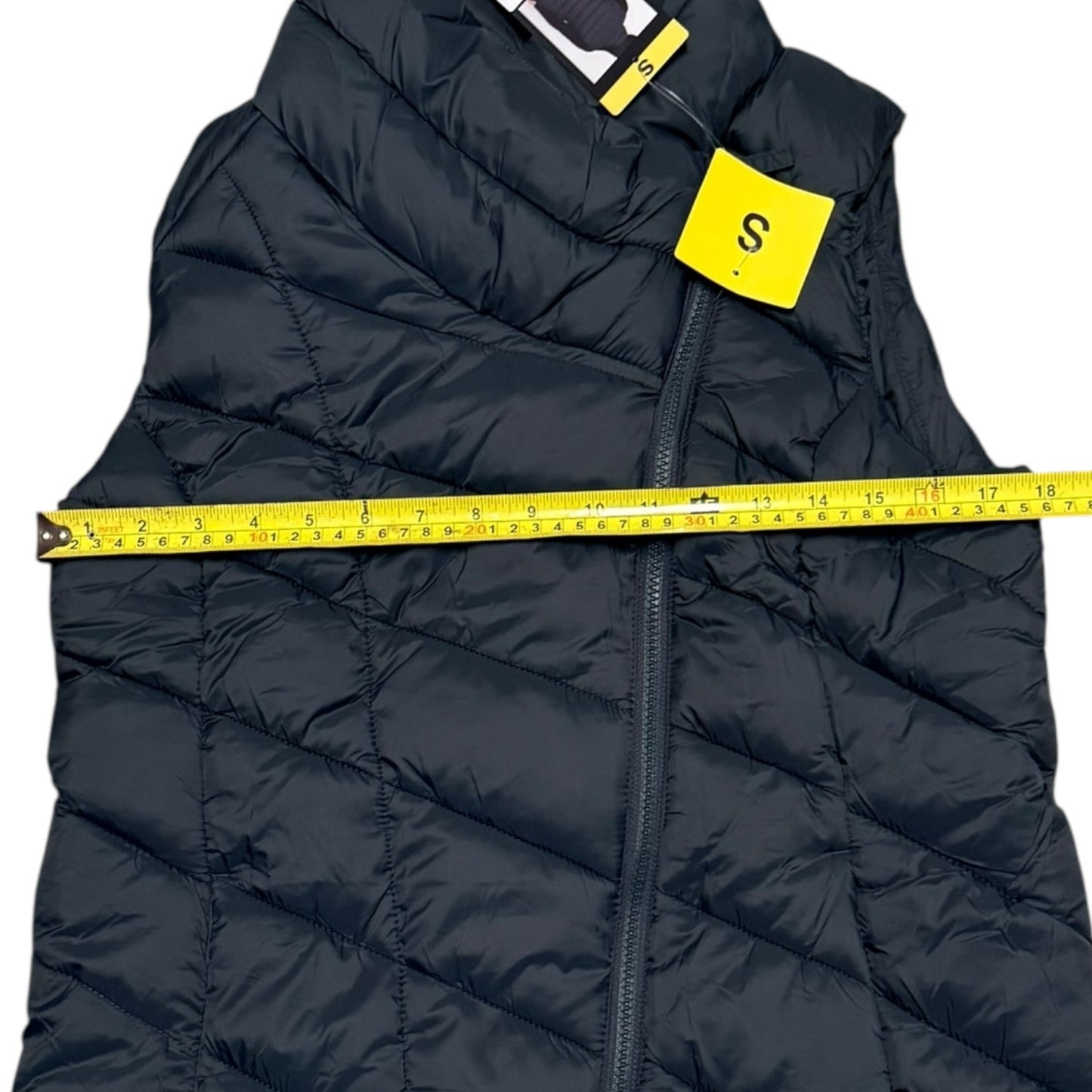 Black puffer vest with a measuring tape and size tag on a white background