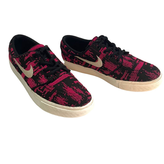A pair of Nike low-top sneakers featuring a black and vibrant pink abstract patterned upper, black laces, and a white sole.
