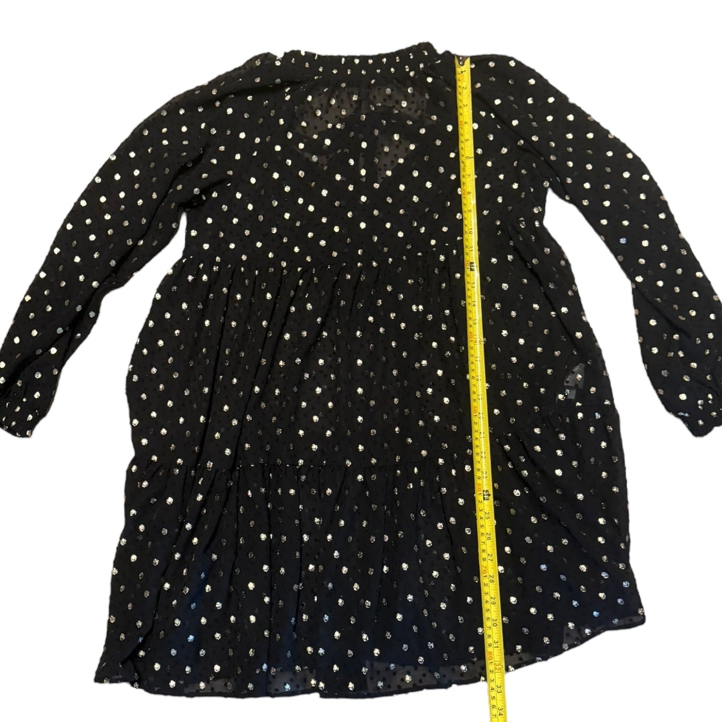 Black dress with white polka dots and a yellow measuring tape on a white background