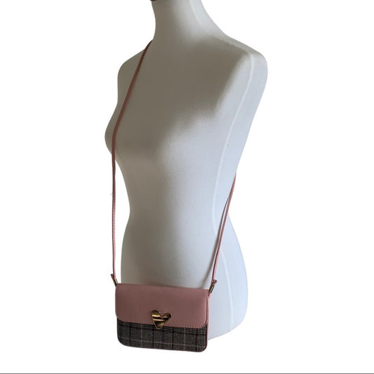A pink crossbody bag with a plaid lower panel and gold heart-shaped clasp, displayed on a white mannequin torso against a white background.