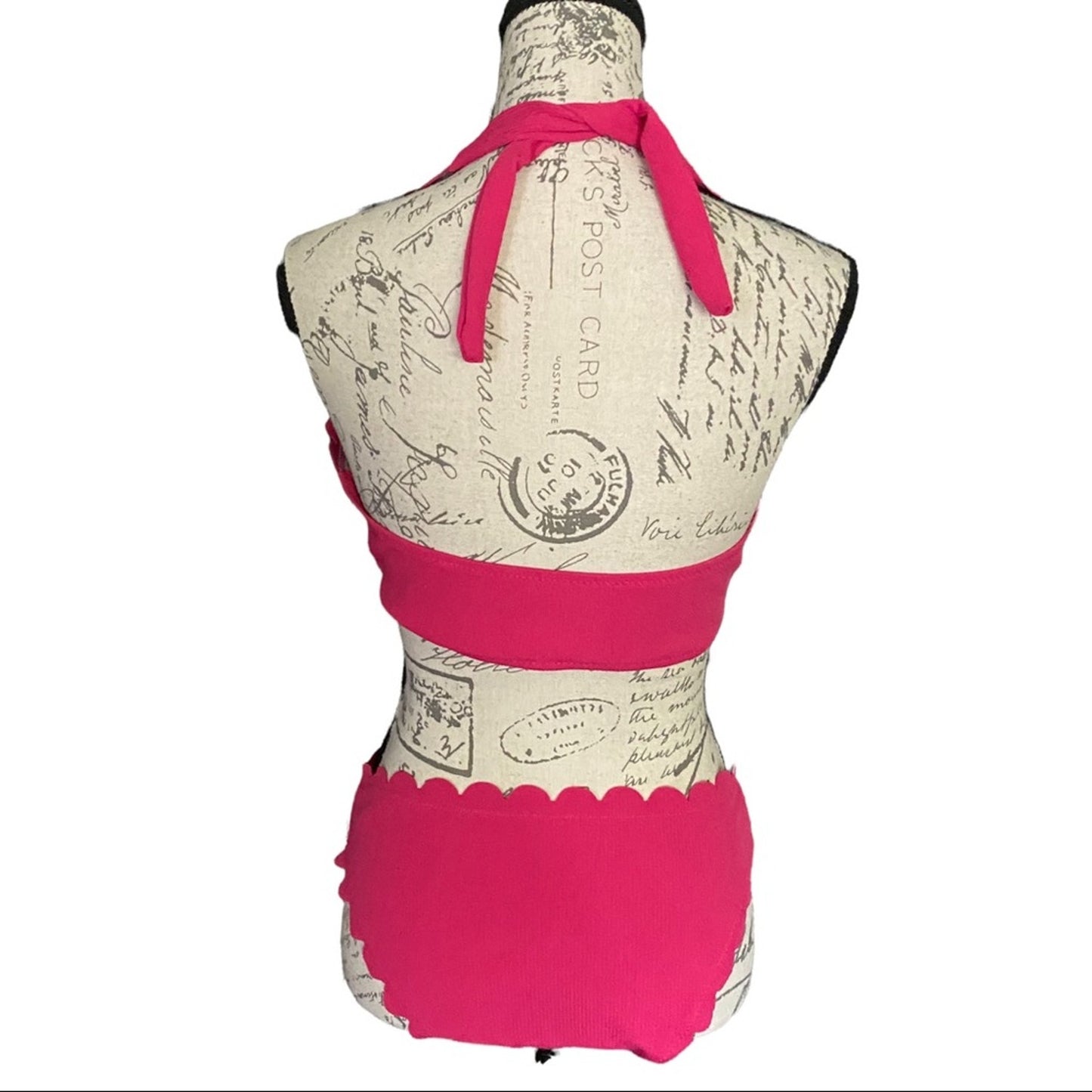 A bright pink halter bikini top and matching bottoms displayed on a vintage-style fabric dress form mannequin against a white background.