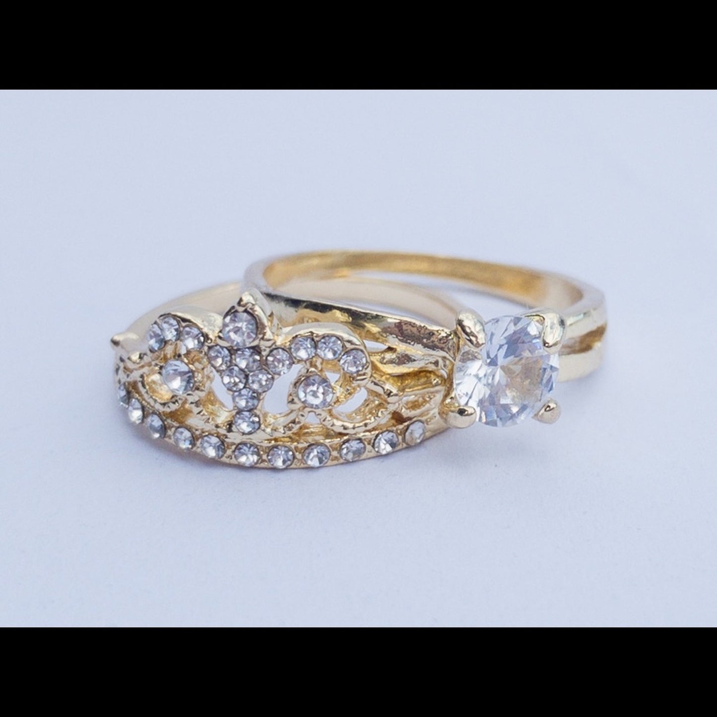 A gold ring with a large clear round-cut center stone and multiple small clear accent stones, photographed on a plain light background.