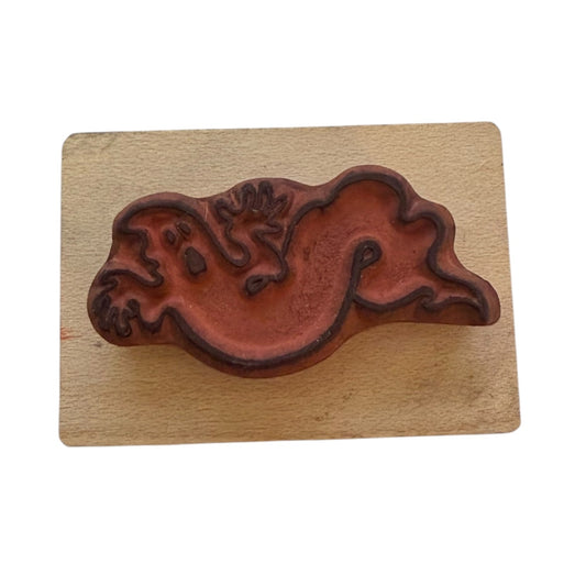 Wooden stamp with a red ghost impression on a wooden block