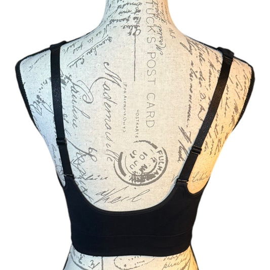 Black bra shown from the back on a vintage-style dress form mannequin, featuring double shoulder straps and a wide supportive band.