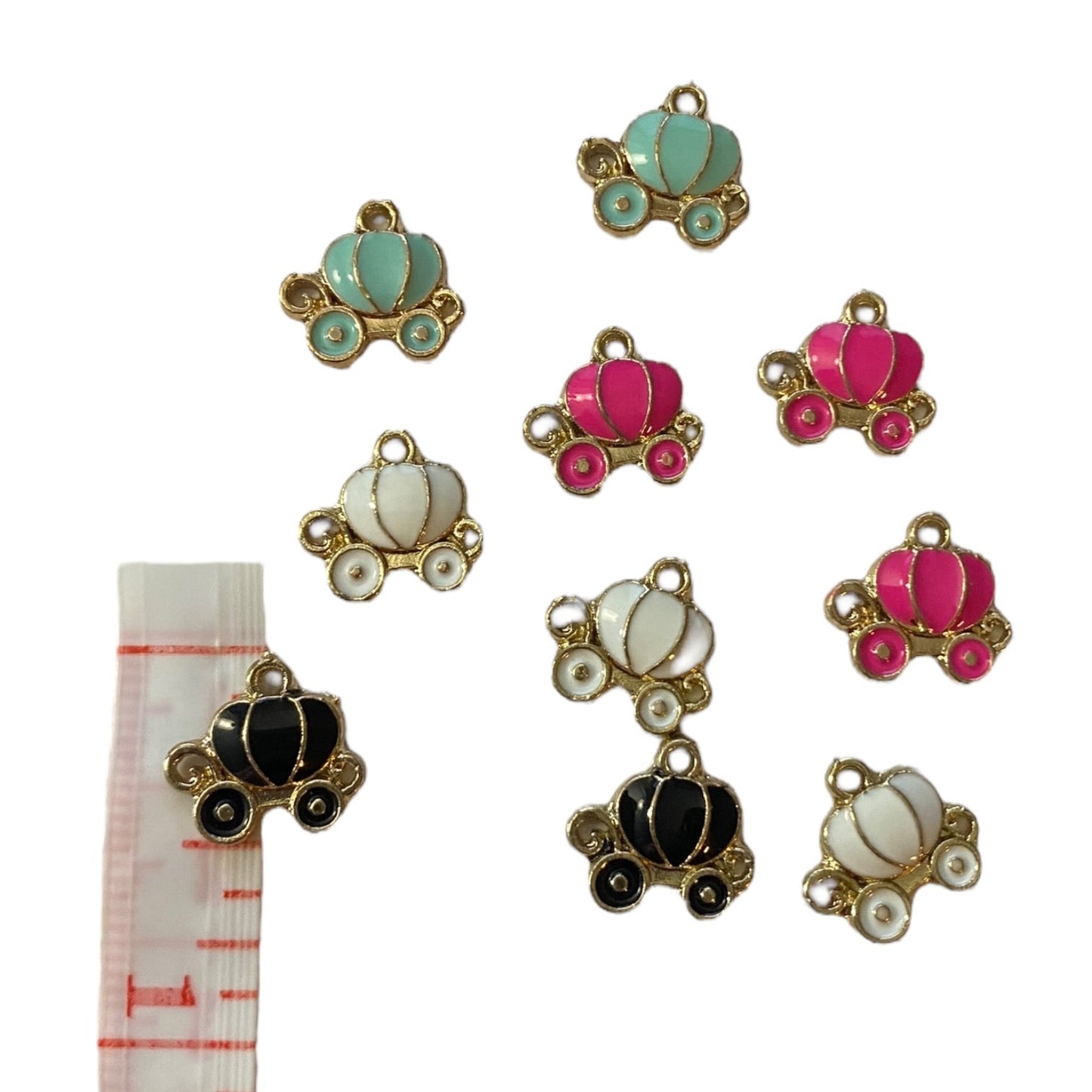 Set of colorful pumpkin carriage charms with a measuring tape for scale on a white background