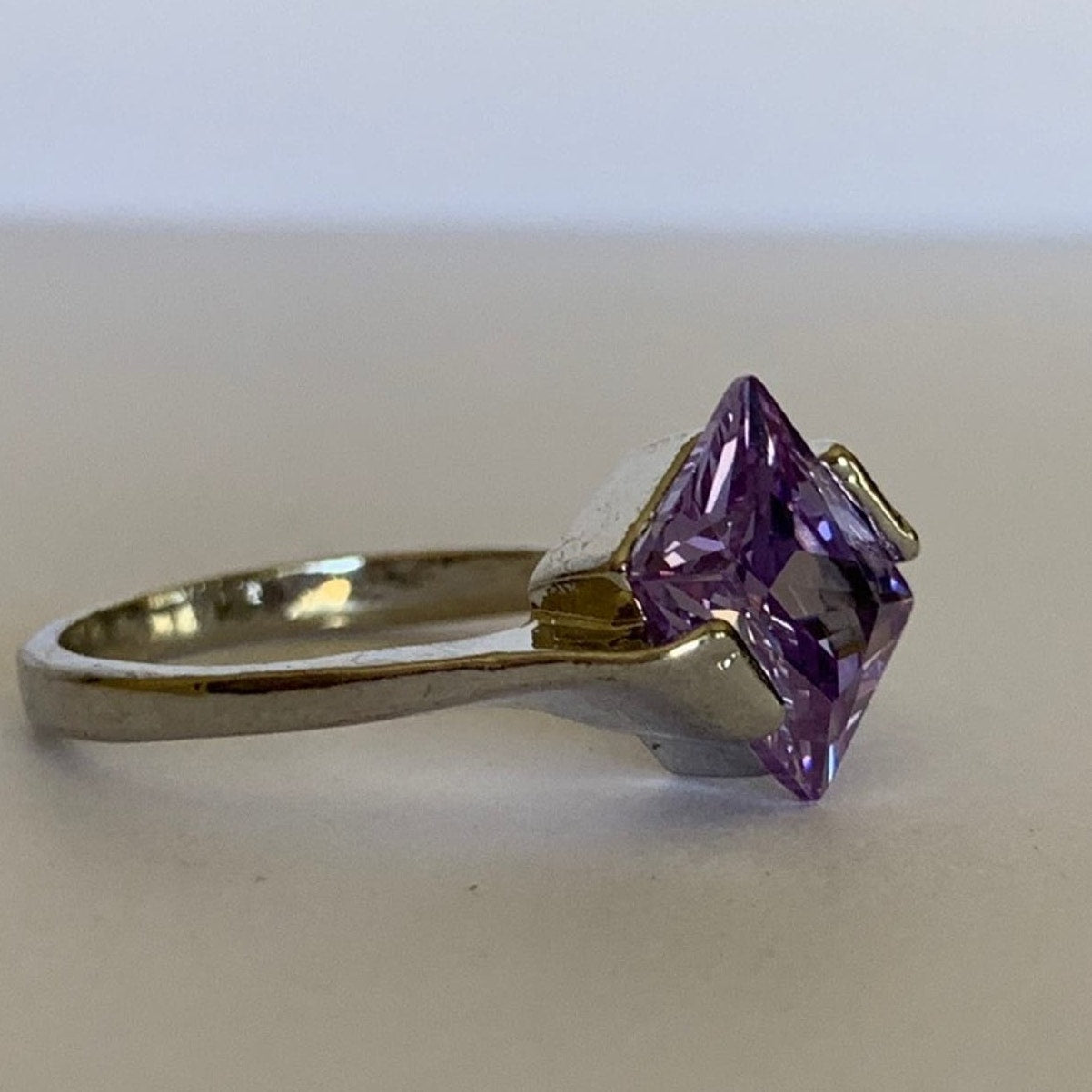 Side of Ring with a purple gemstone on a plain background