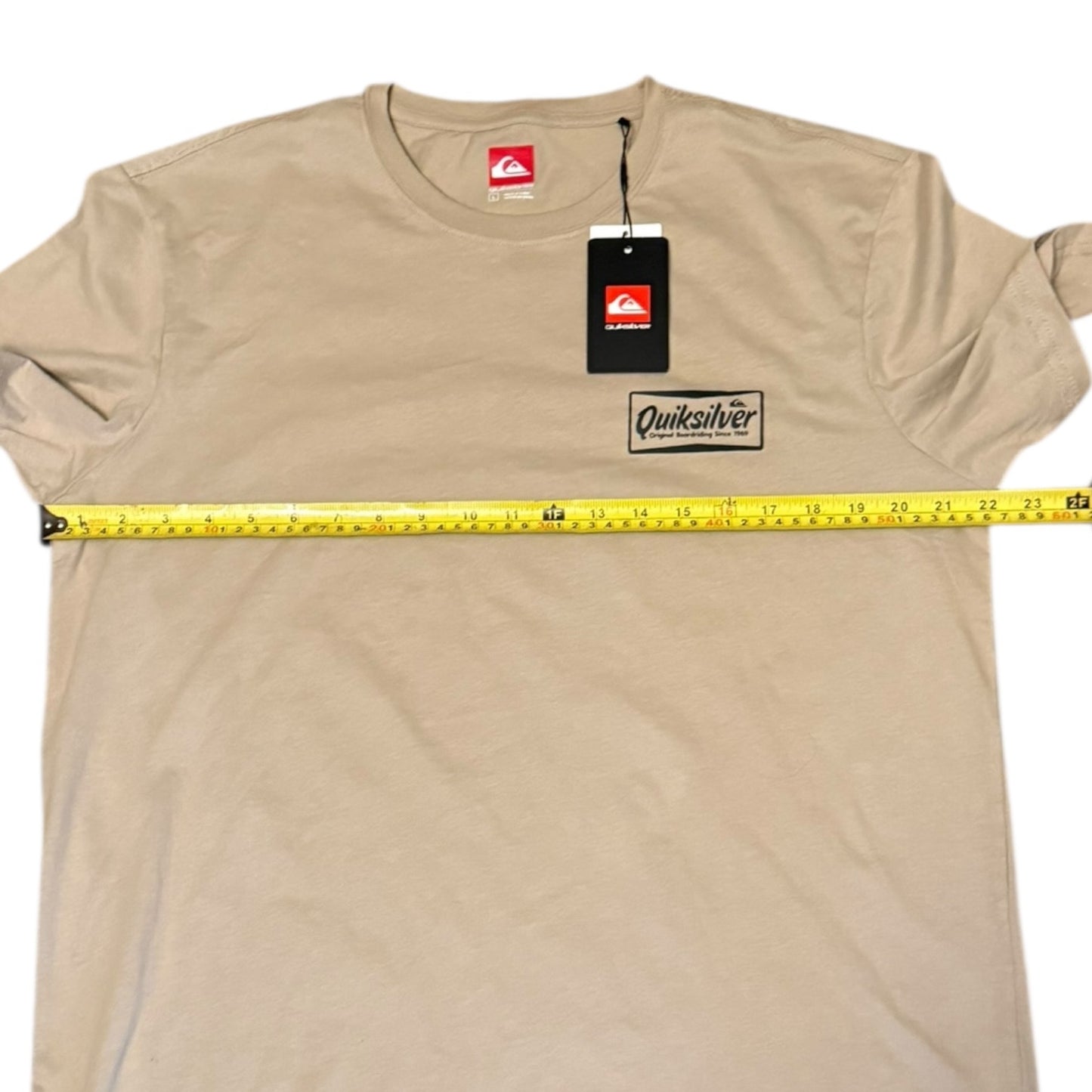 Beige t-shirt with Quiksilver logo and measuring tape on a white background