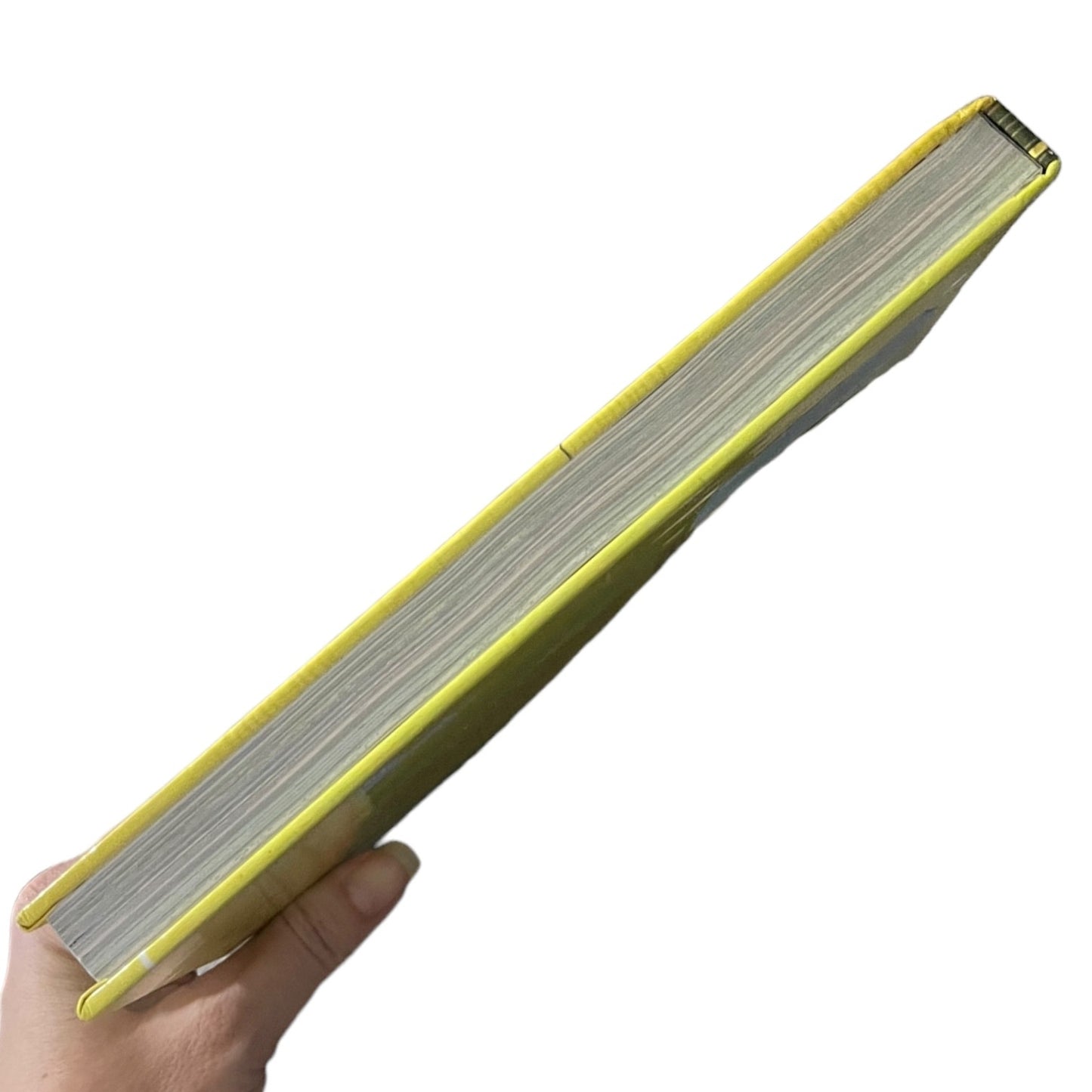 A hand holding a thick hardcover book or notebook at an angle against a plain white background, showing a bright yellow-green cover and numerous white pages.