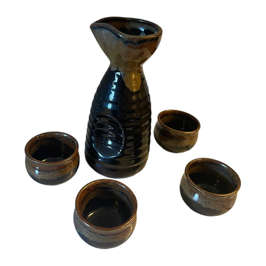 A five-piece ceramic sake set featuring a glossy dark blue-black carafe and four matching small cups with brown and gold glaze accents, arranged on a plain white background.