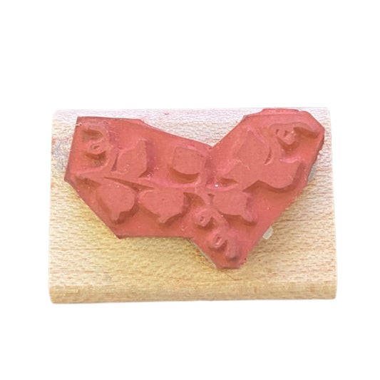 A rubber stamp on a light-colored wooden block, photographed against a plain white background.