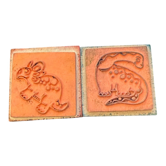 2 rubber stamps with embossed dinosaur designs on a white background