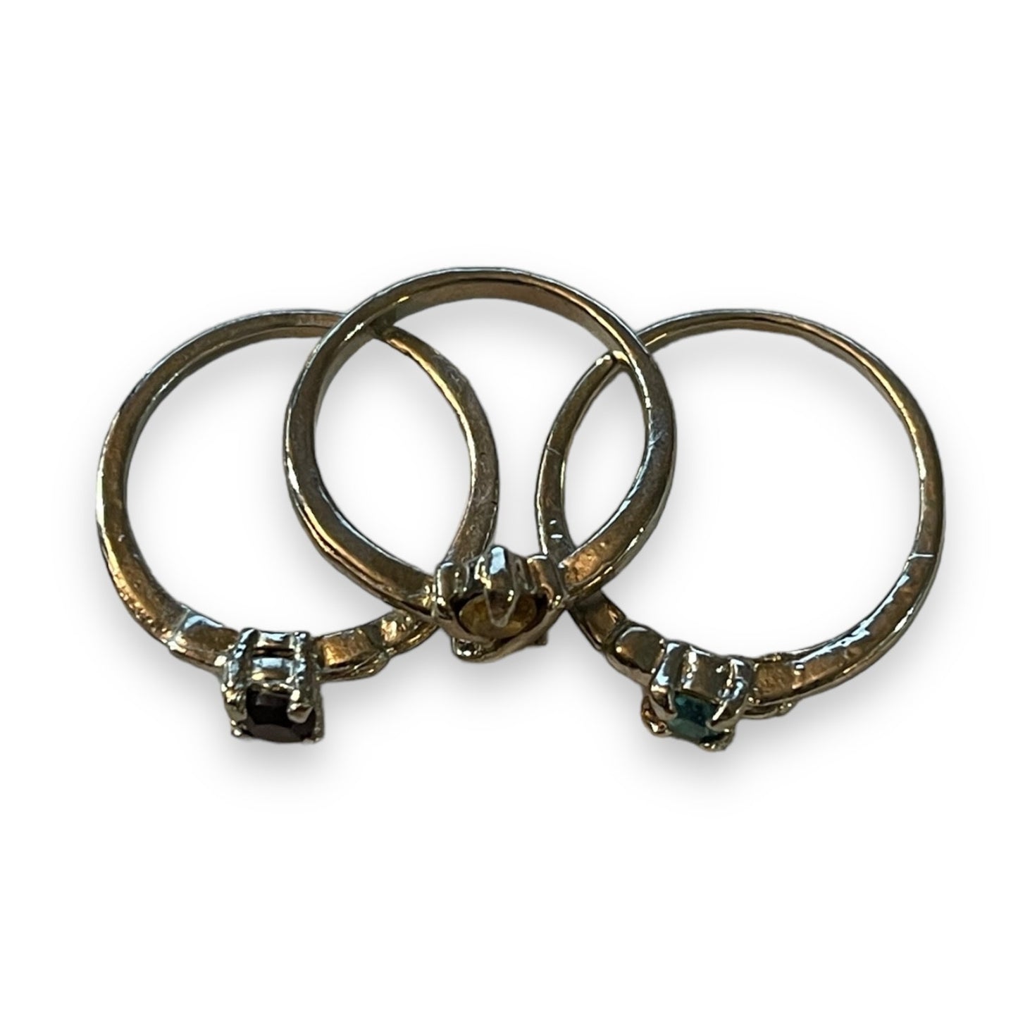 Three silver rings with small round-cut gemstones, arranged overlapping on a plain white background.