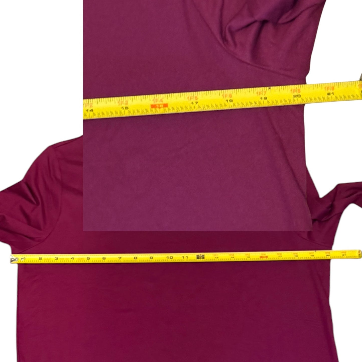 A purple shirt laid flat on a white background, with a yellow measuring tape stretched horizontally across the chest and sleeve area to show garment dimensions.