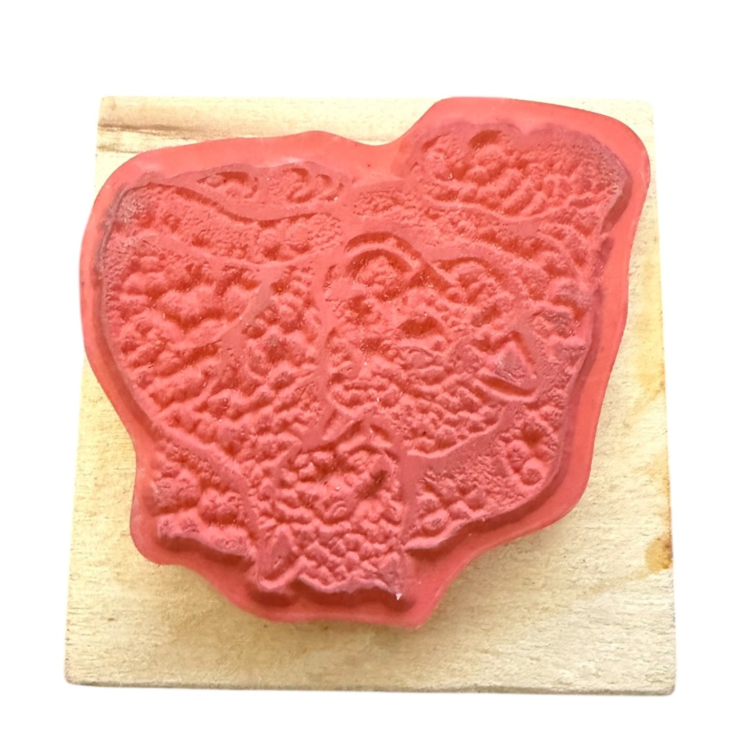 A red rubber stamp , mounted on a light-colored wooden block against a white background.